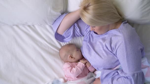 Bakımlı genç anne uykulu kız bebeği emziriyor, yeni doğan bebek beslenme programı... — Stok video