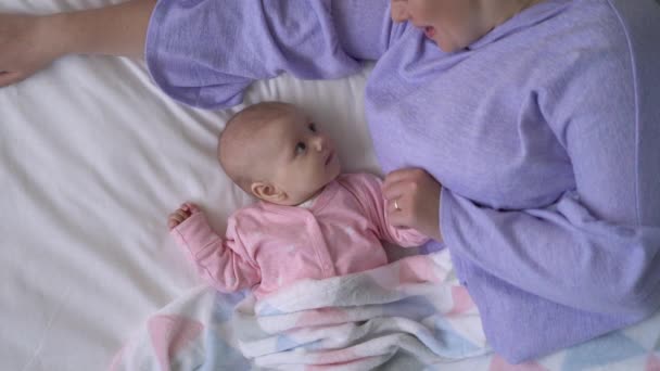 快乐的年轻妈妈在床上和可爱的婴儿玩耍，爱与关怀，甜蜜的母性 — 图库视频影像