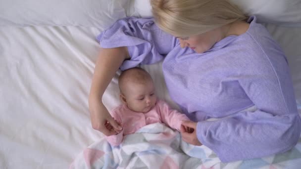 Anne ve bebek yatakta, sabah uyandıktan sonra oynuyorlar, birlikte vakit geçiriyorlar. — Stok video