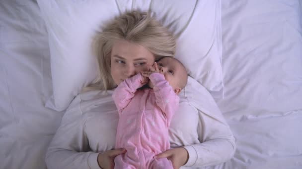 Šťastná maminka objímání a líbání rozkošná holčička na posteli, plná lásky emoce — Stock video
