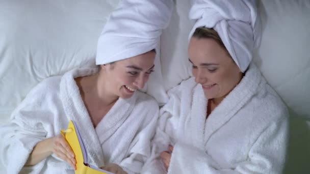 Εφηβικά κορίτσια διαβάζουν ημερολόγιο στο κρεβάτι, μοιράζονται μυστικά και γελάνε, φιλία — Αρχείο Βίντεο