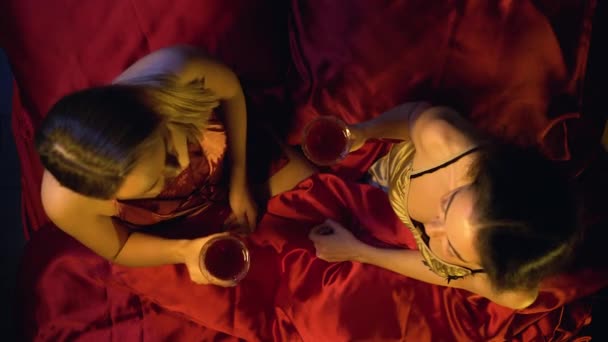 Ρομαντικό ατμόσφαιρα ημερομηνία, λεσβιακό ζευγάρι clinking γυαλιά, πίνοντας κρασί στο κρεβάτι — Αρχείο Βίντεο