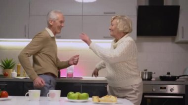 Mutfakta müzik eşliğinde dans eden, birlikte eğlenen son sınıf çifti.