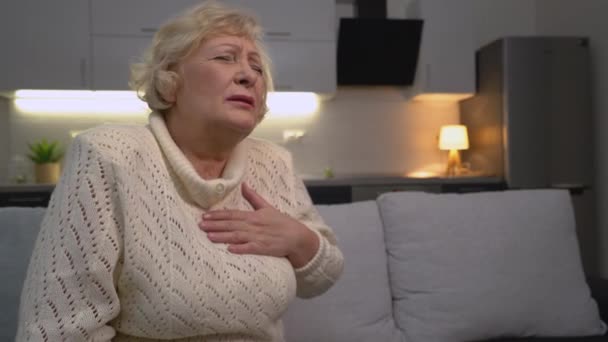 Пожилая женщина страдает дискомфортом груди, ишемической болезнью сердца, здоровьем — стоковое видео
