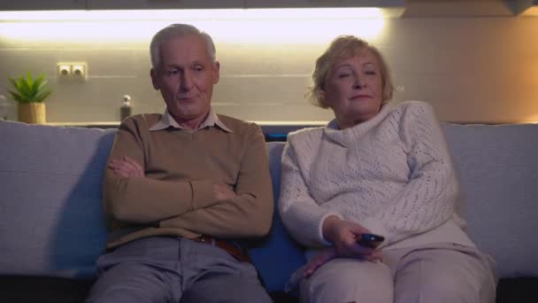 Ofendido hombre y mujer sentado en casa en el sofá delante de la televisión, conflicto familiar — Vídeos de Stock