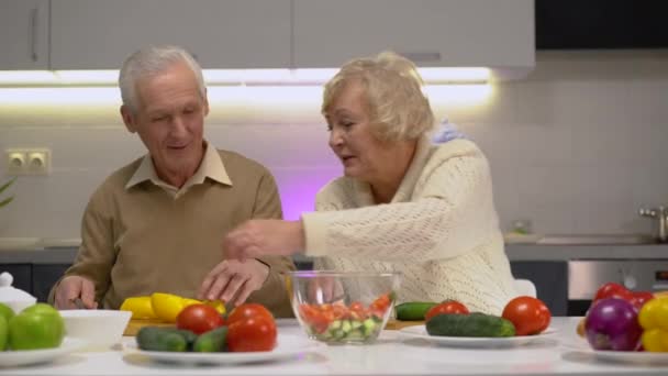 Aktive alte Frau und Mann schneiden frisches Gemüse in der Küche, gesunder Lebensstil — Stockvideo