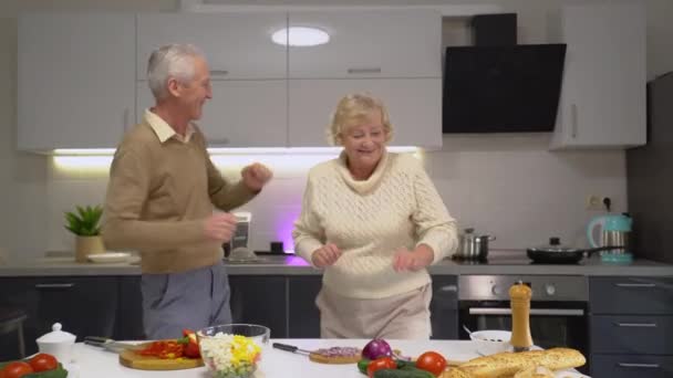 Pareja de ancianos juguetones bailando en la cocina, disfrutando del tiempo divertido, matrimonio feliz — Vídeo de stock