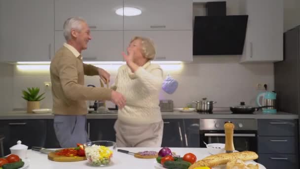 Doux couple de personnes âgées dansant dans la cuisine, profitant du temps ensemble, mode de vie actif — Video