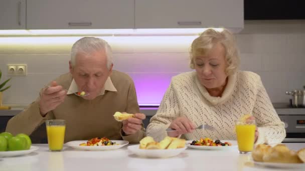 Здоровая пожилая пара наслаждается овощным салатом и свежим хлебом на завтрак — стоковое видео