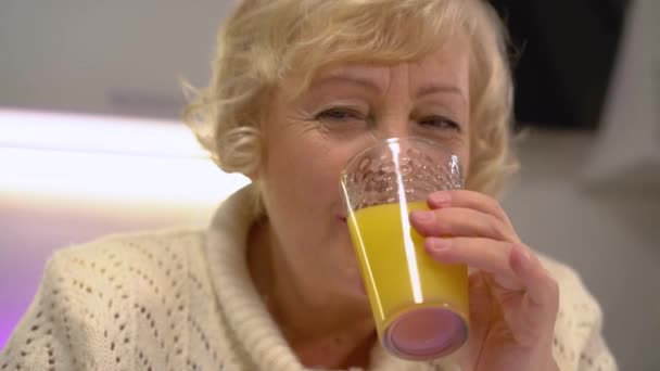 Idős nő és férfi friss narancslevet iszik, egészséges táplálkozás az aktív életért — Stock videók