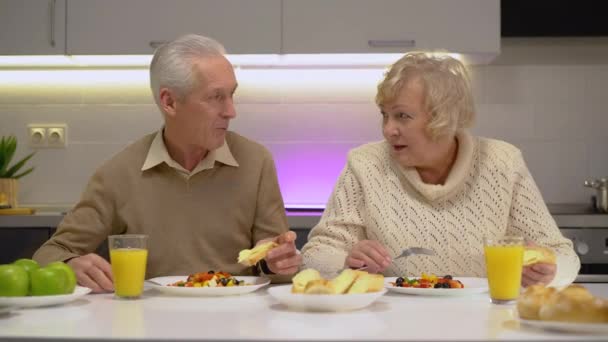 Веселые пожилые пары едят здоровый завтрак вместе дома, питание — стоковое видео
