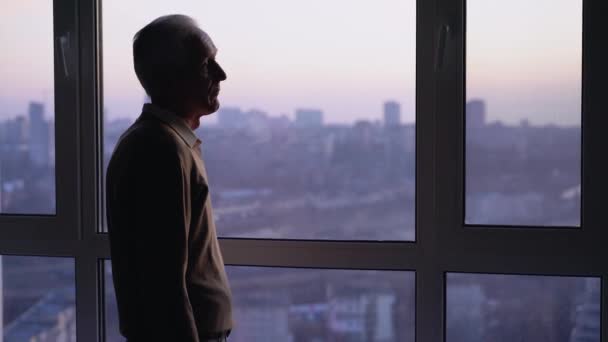 Уставший больной стоит один у окна, проблемы со здоровьем, кризис одиночества — стоковое видео