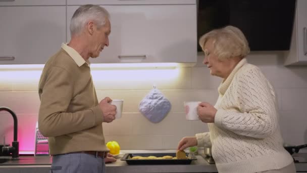 Senioren genieten van leuk gesprek, zelfgemaakte koekjes eten in de keuken — Stockvideo