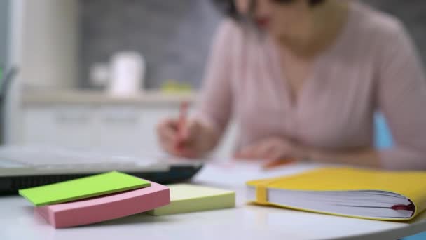 Haftnotizen und gelbes Notizbuch auf dem Tisch, Designerin arbeitet am Hintergrund — Stockvideo