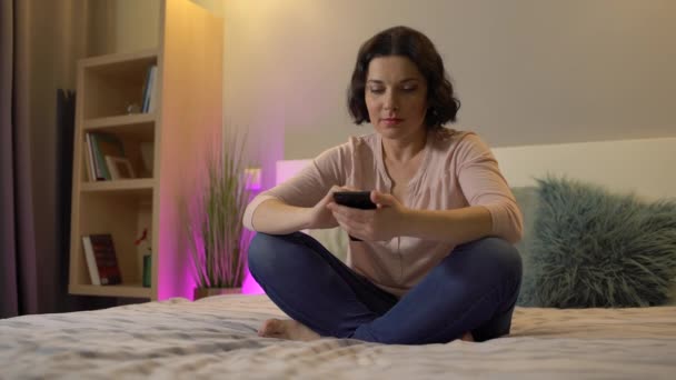 Attractive woman scrolling photos on smartphone, relaxing at home, online app — Stock Video