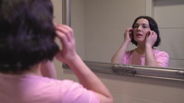 Pretty middle-aged woman looking at mirror reflection and smiling, beauty care — Stock Video