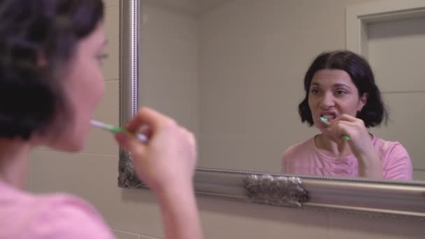 Junge Frau beim Zähneputzen im Badezimmer, tägliche Morgenroutine, Mundpflege — Stockvideo