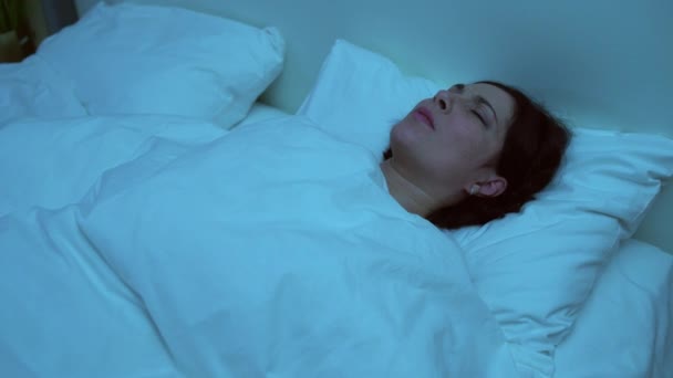 Genç bir kadın kabus görüyor, geceleri yatakta yatıyor, travma sonrası stres bozukluğu yaşıyor. — Stok video