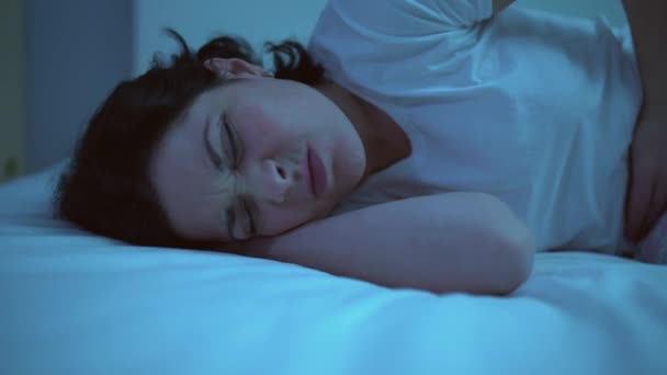 Üzgün kadın karın ağrısından kıvranıyor, yatağa uzanıyor ve acı dolu kramplar çekiyor. — Stok video