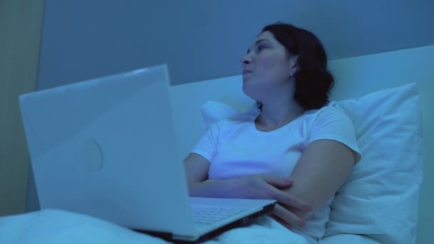 Gelangweilte Frau schaut Video auf Laptop im Bett, verärgert über schlechte Nachrichten, Schlaflosigkeit — Stockvideo