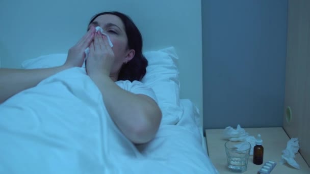 Больная женщина, сморкающаяся в ткани, измученная, лежащая в постели, проблемы со здоровьем — стоковое видео