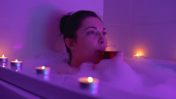 Sakin bir kadın sıcak köpüklü banyoda rahatlayan bir bardak şarap içiyor, stresi azaltıyor. — Stok video