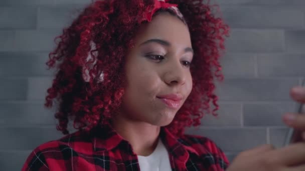 Adolescente afroamericano desplazando fotos en el teléfono inteligente, escuchando música — Vídeos de Stock