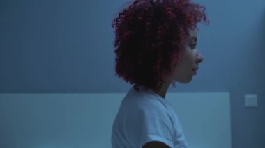 Afro-Amerikan kadın yatakta uzanıyor, hafta sonları dinleniyor, rahat bir yatak odası var.