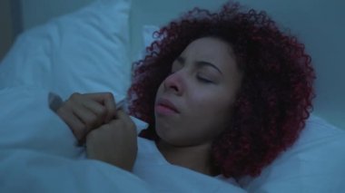 Hapşıran kadın yatakta uzanıyor, burnunu mendille siliyor, grip virüsü, hastalık...