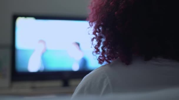 Young red-haired woman watching film on tv at home, free time entertainment — Stock Video