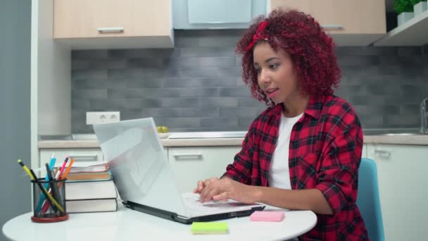 Emsiges Mädchen mit gemischter Rasse, das am Laptop zu Hause arbeitet und Notizen auf Aufkleber schreibt, Bildung — Stockvideo