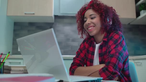 Счастливая девушка в наушниках проводит телефонную конференцию на ноутбуке, берет онлайн-уроки — стоковое видео