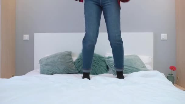 Молодая женщина прыгает на кровати дома, удобный матрас, счастье, свобода — стоковое видео