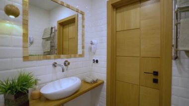 Modern banyo içi, beyaz lavabo ve ayna, otel servisi.
