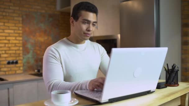 Ung man skriver på laptop, manlig programmerare arbetar hemma, frilansprojekt — Stockvideo