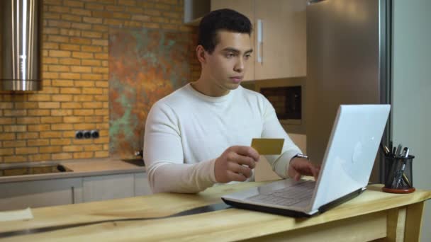 Young man shopping online, paying with credit card, goods show up in stop motion — Stock Video