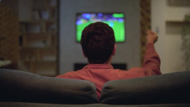 Разочарованный спортивный болельщик смотрит матч по телевизору, недоволен результатом, проигрывает ставку — стоковое видео
