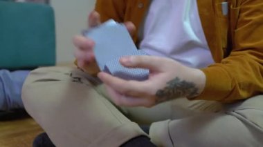 Adam kağıt karıştırıyor, yerde oturuyor, boş zaman, masa oyunu, hobi