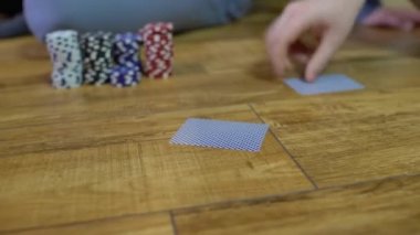 Genç adam kağıt dağıtıyor, arkadaşlarıyla poker oynuyor, eğleniyor.