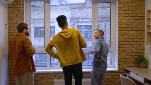 Group of multi-ethnic friends talking, looking at window and drinking whisky — Stock Video