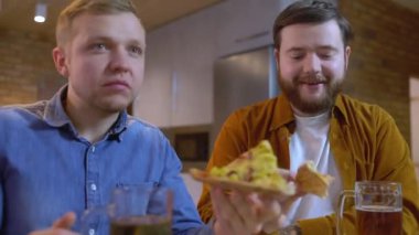 Neşeli gençler bira içiyor, hedefi kutluyor, birlikte maç izliyorlar.