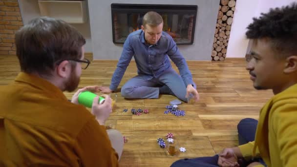 Jovens sacudindo xícara, jogando dados de poker em casa, companheiros passando tempo juntos — Vídeo de Stock