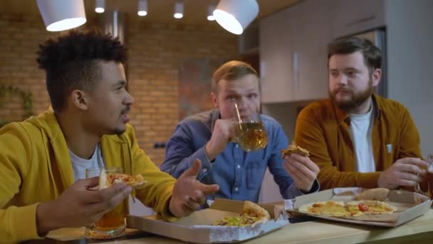 Amigos masculinos emocionales discutiendo el juego deportivo, viendo la televisión, comiendo pizza — Vídeos de Stock