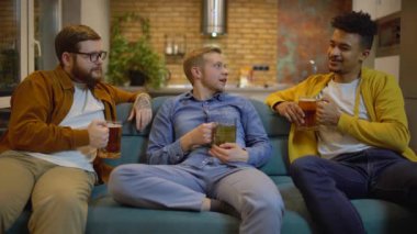 Mutlu gençler bira içiyor, kanepede konuşuyor, arkadaşlarıyla iletişim kuruyor.