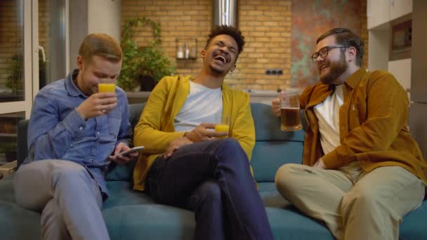 Drie jongemannen die samen grappen maken en lachen, drankjes drinken op het feest. — Stockvideo