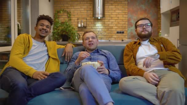 Multiculturele vrienden kijken comedy show op tv en kauwen popcorn thuis — Stockvideo