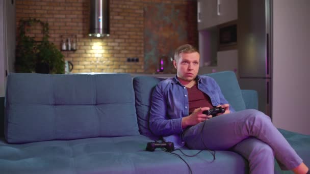 Dwóch przyjaciół grających w konsolę do gier wideo na kanapie, bawiących się razem, spędzających wolny czas — Wideo stockowe