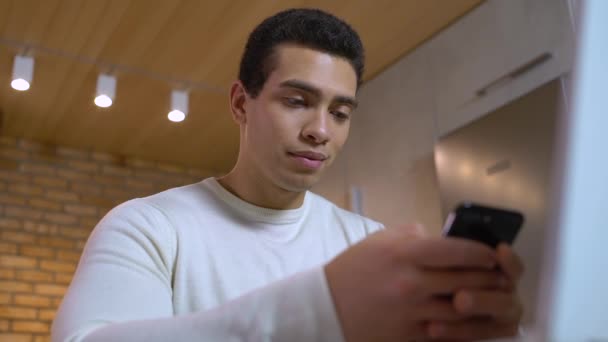 Смойлинг фрилансер, работающий на смартфоне дома, читающий сообщения, приложение электронной почты — стоковое видео
