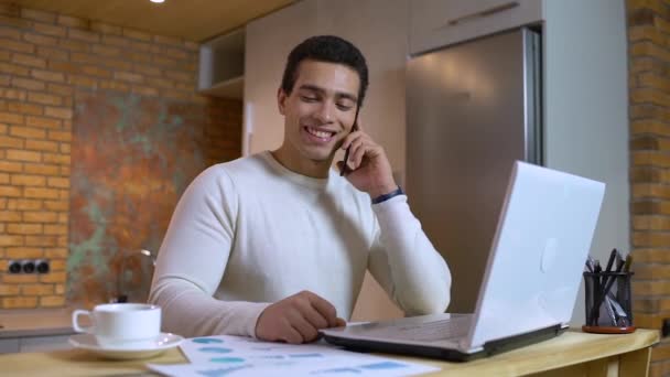 Feliz hombre de negocios de raza mixta hablando por teléfono, mirando el informe de ventas, trabajo — Vídeo de stock