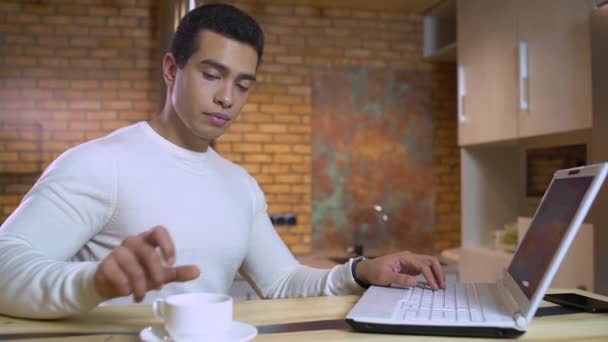 Jonge freelancer werkt aan laptop, drinkt thee, schrijft journalist artikel — Stockvideo
